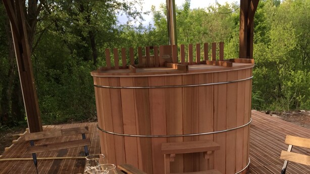 A wooden deck with a long table set for dining, surrounded by a wooden structure with a cylindrical chimney. - Le Domaine des Tuileries (Salins)