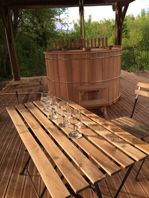 A wooden deck with a long table set for dining, surrounded by a wooden structure with a cylindrical chimney. - Le Domaine des Tuileries (Salins)