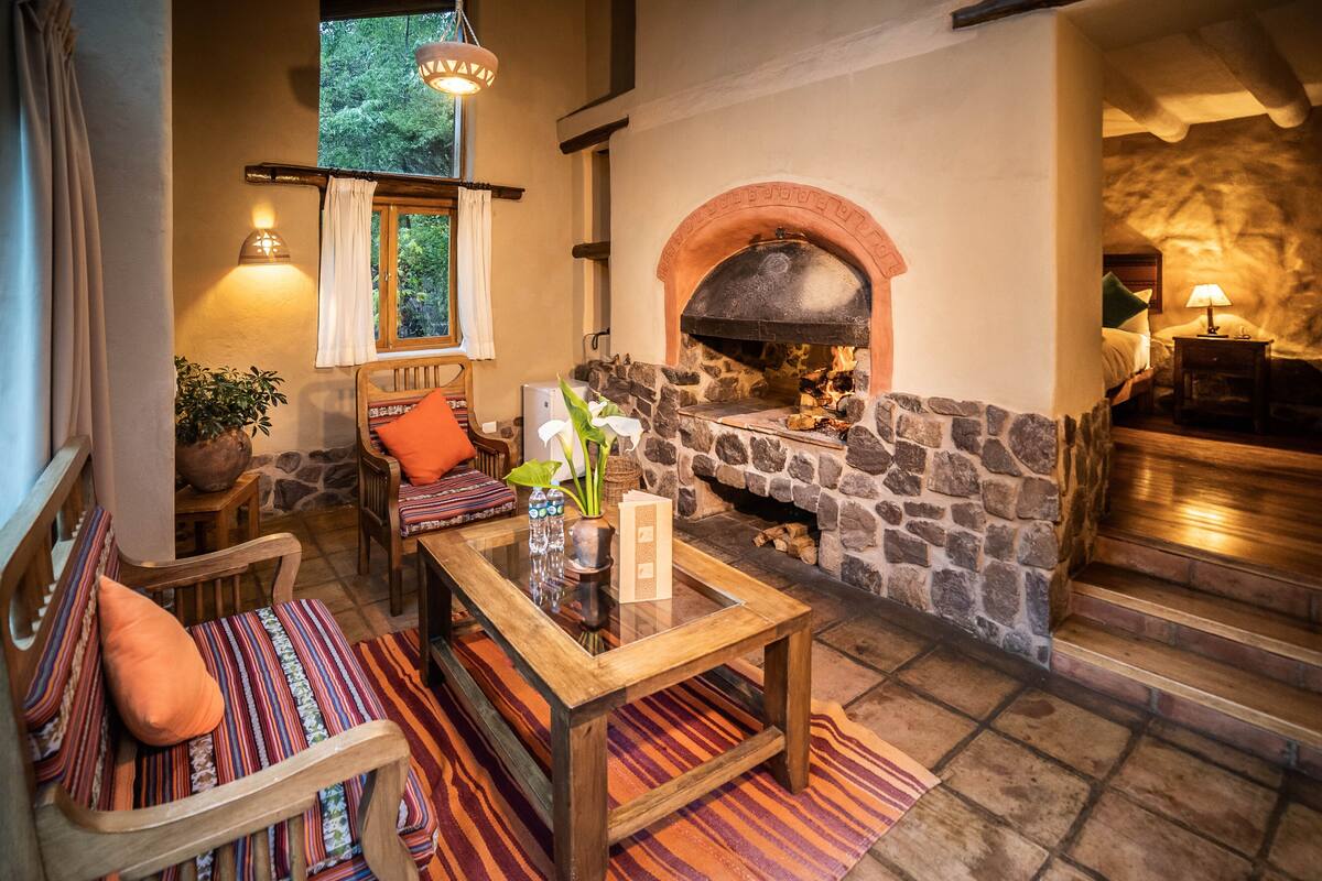 A cozy living area with a stone fireplace, comfortable seating, and a view of the outdoors.