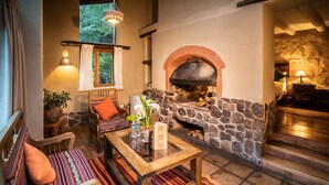 A cozy living area with a stone fireplace, comfortable seating, and a view of the outdoors. - Sacred Dreams Lodge (Urubamba)