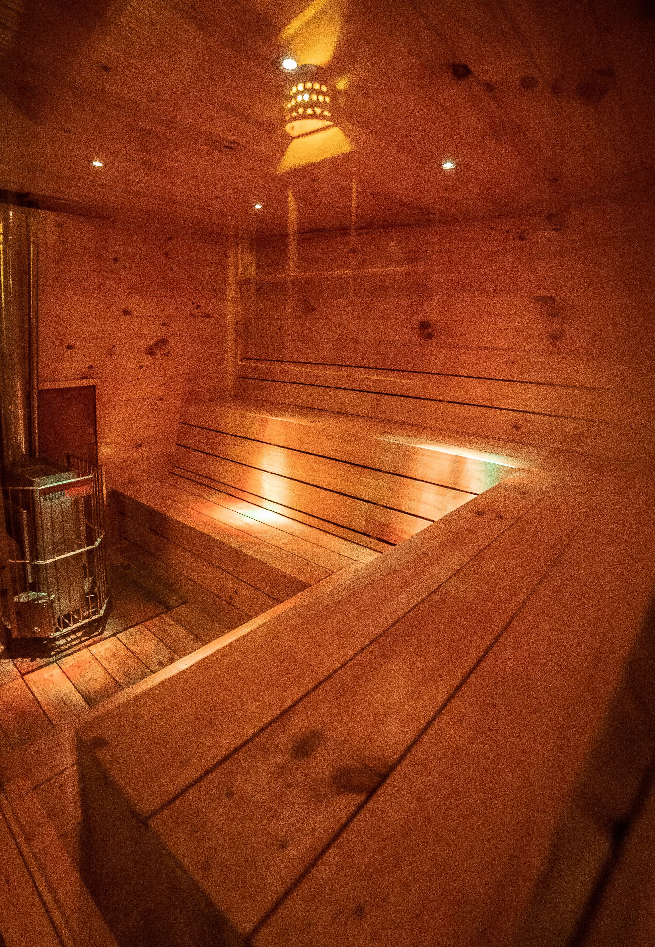 Una sauna de madera con bancos y cerramiento de vidrio.