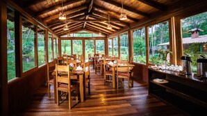 A wooden interior with tables and chairs, large windows, and a coffee station. - Sacred Dreams Lodge (Urubamba)