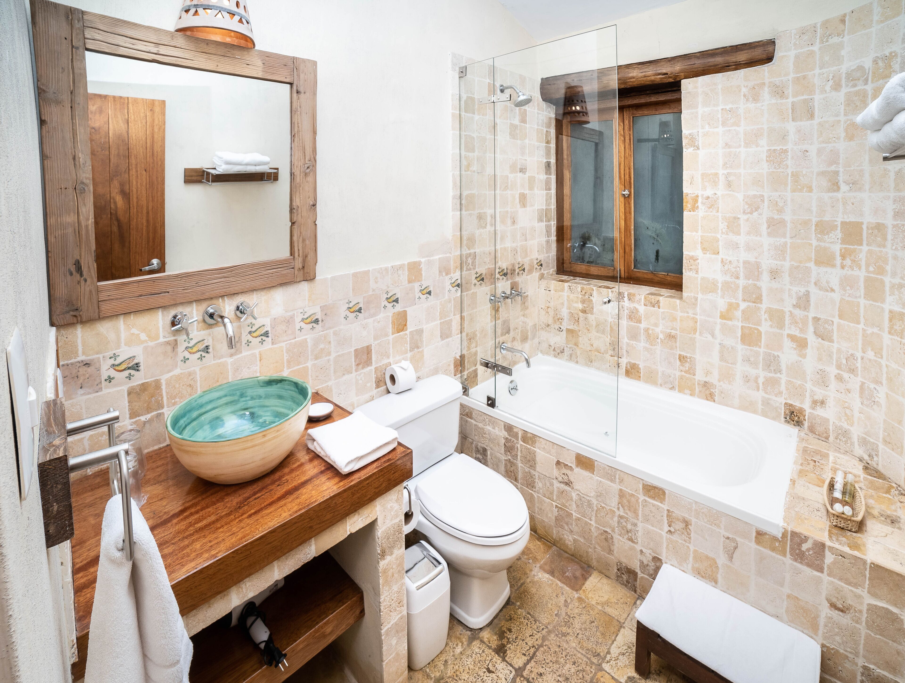 A bathroom with a wooden vanity, a glass-enclosed shower, a white toilet, and a bathtub.