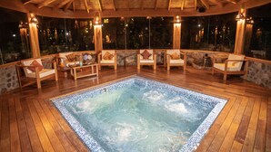 A hot tub surrounded by wooden deck chairs and stone walls. - Sacred Dreams Lodge (Urubamba)