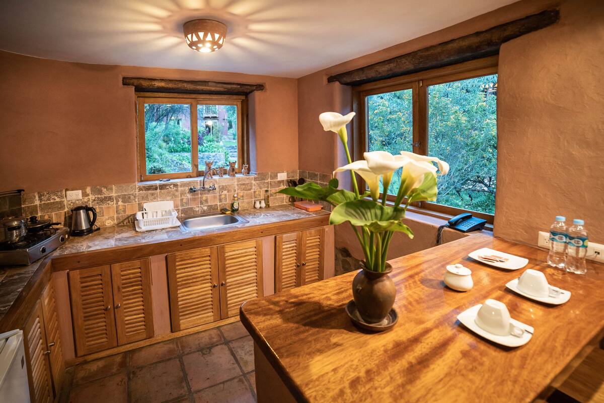 A kitchen with wooden cabinets, a sink, and a window overlooking greenery.