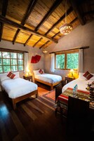 Una habitación acogedora con dos camas, piso de madera y techo rústico.