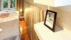 Un dormitorio con cama, mesita de noche, ventana con cortinas y decoración en la pared.