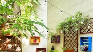 Un patio acogedor con muebles de madera, plantas en macetas y un muro de piedra.