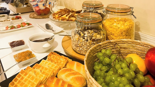 Un bufé de desayuno con gofres, pasteles y un bol de uvas.