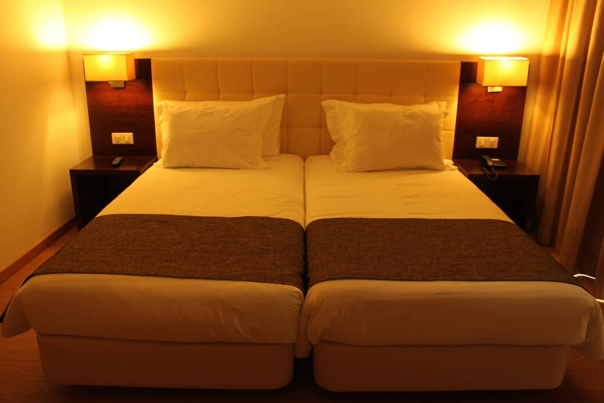 Een hotelkamer met een tweepersoonsbed en twee nachtkastjes, elk met een lamp.