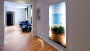 A modern hotel room with a wooden floor, a seating area with a small table, and a large window with a view of the sea. - Hostal Bcn Ramblas (Barcelona)