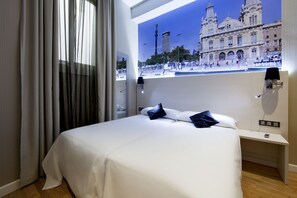 Una camera d'albergo con un letto, un comodino, una lampada e vista su un edificio storico.