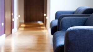 A hotel lobby with a wooden floor and rows of blue upholstered chairs. - Hostal Bcn Ramblas (Barcelona)
