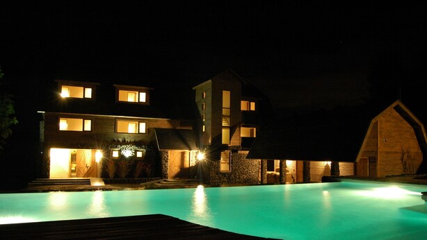 Un hotel moderno con piscina, varias habitaciones de huéspedes y una gran estructura tipo granero.