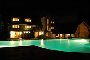 Una piscina al aire libre, sombrillas, sillones reclinables de piscina