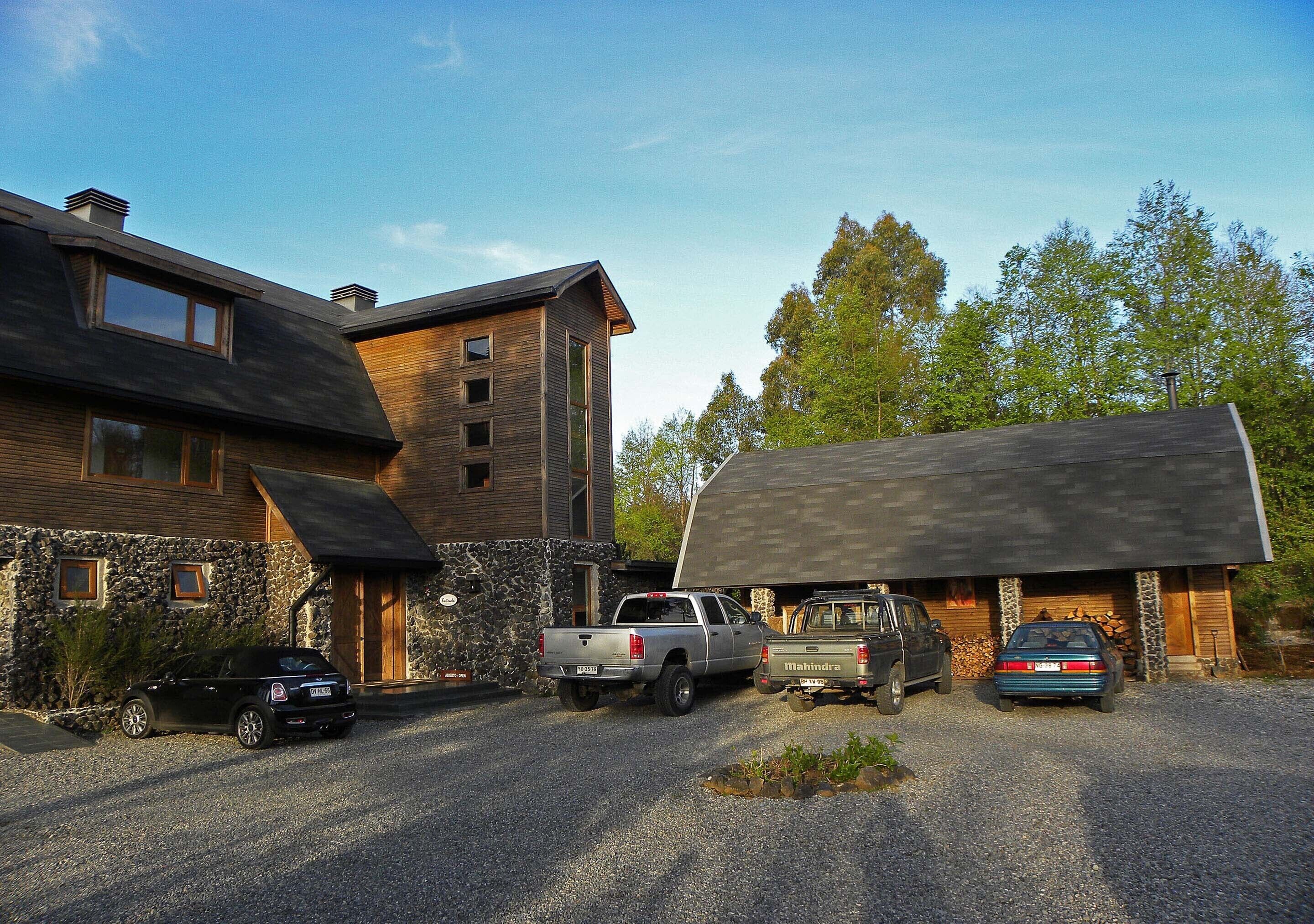 A modern house with a stone facade, a garage, and a gravel driveway.