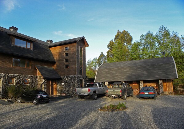 A modern house with a stone facade, a garage, and a gravel driveway. - Hotel CasaEstablo by DOT Boutique (Pucón)