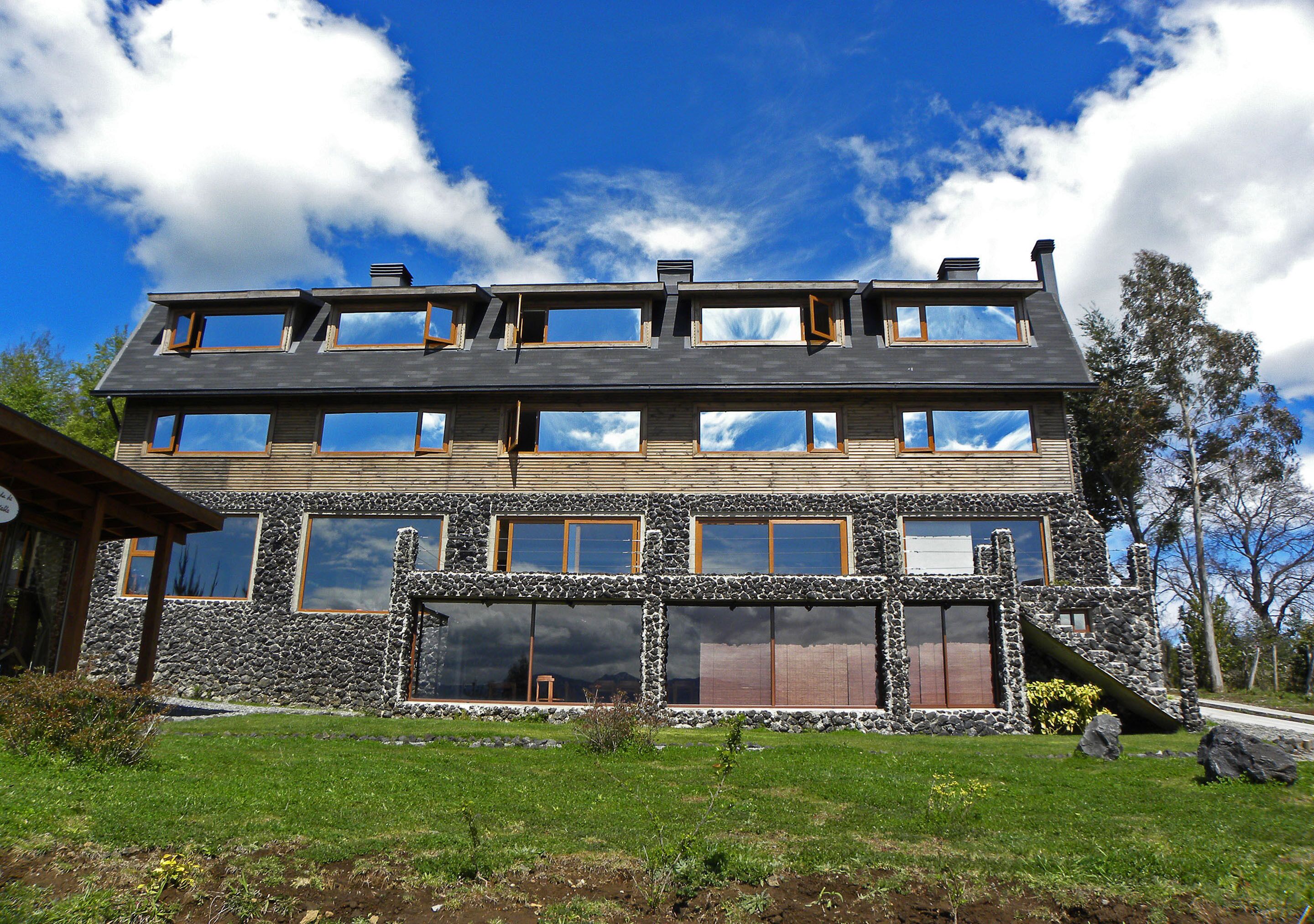 Une maison en pierre à deux étages, dotée de nombreuses fenêtres et d’un toit en pente.