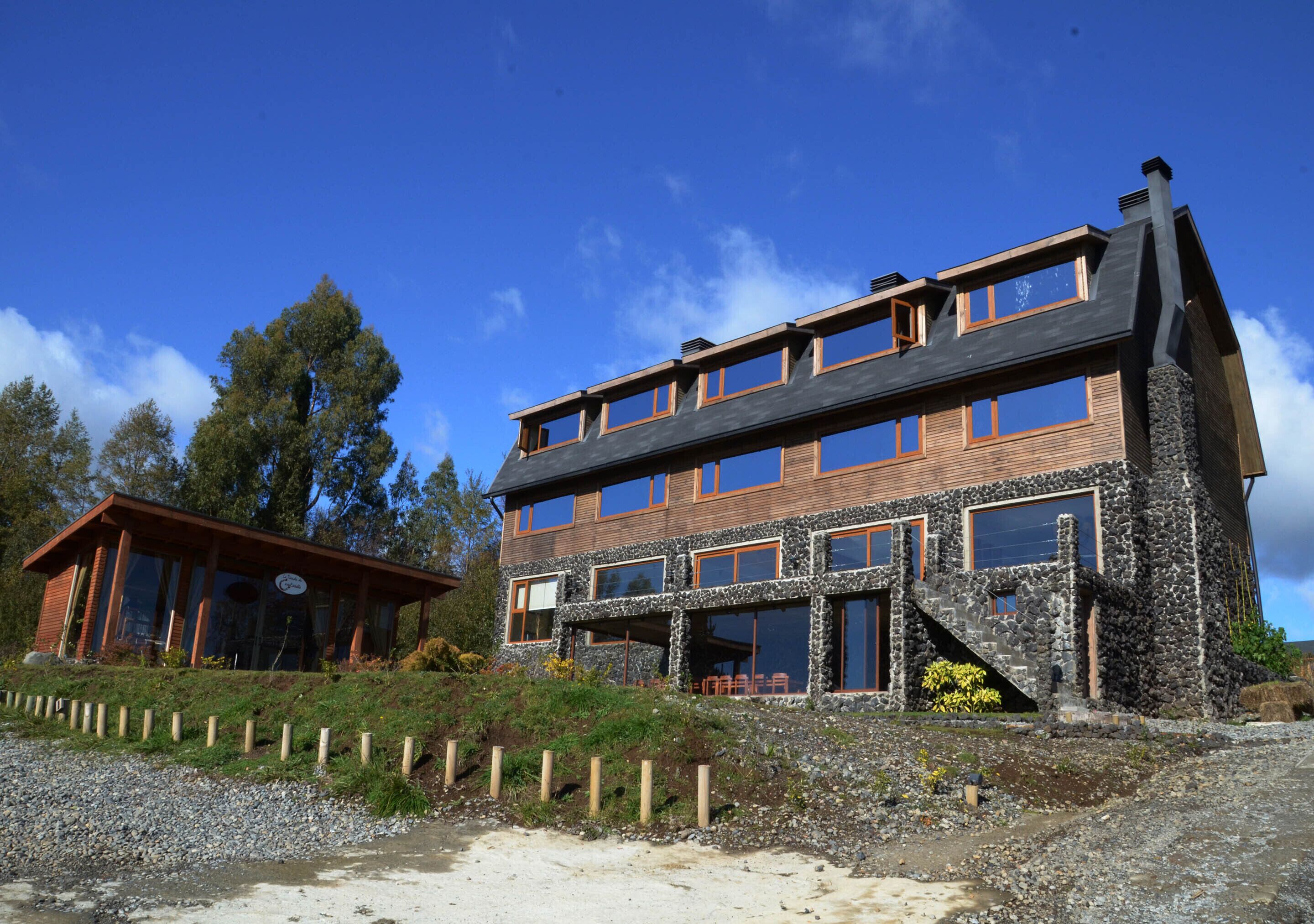 Un edificio de varios pisos con fachada de piedra, ventanas grandes y una terraza de madera.