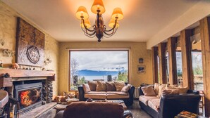 Una sala de estar acogedora con chimenea, un ventanal con vistas y una araña.