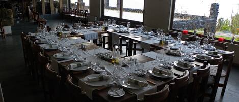 A restaurant with tables set for dining, large windows with a view, and a rustic interior design.