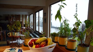 Un comedor con una mesa dispuesta para el desayuno, que incluye un bol de fruta y tazas de café.