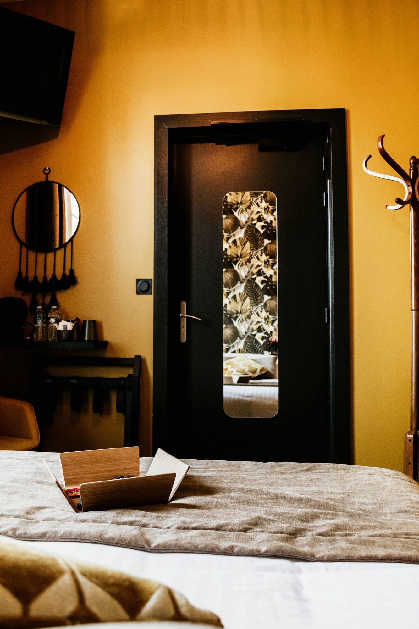 Ein Schlafzimmer mit Bett, Nachttisch, Lampe und einer Tür mit Blumenmuster.