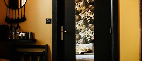 A bedroom with a bed, a bedside table, a lamp, and a door with a floral pattern.