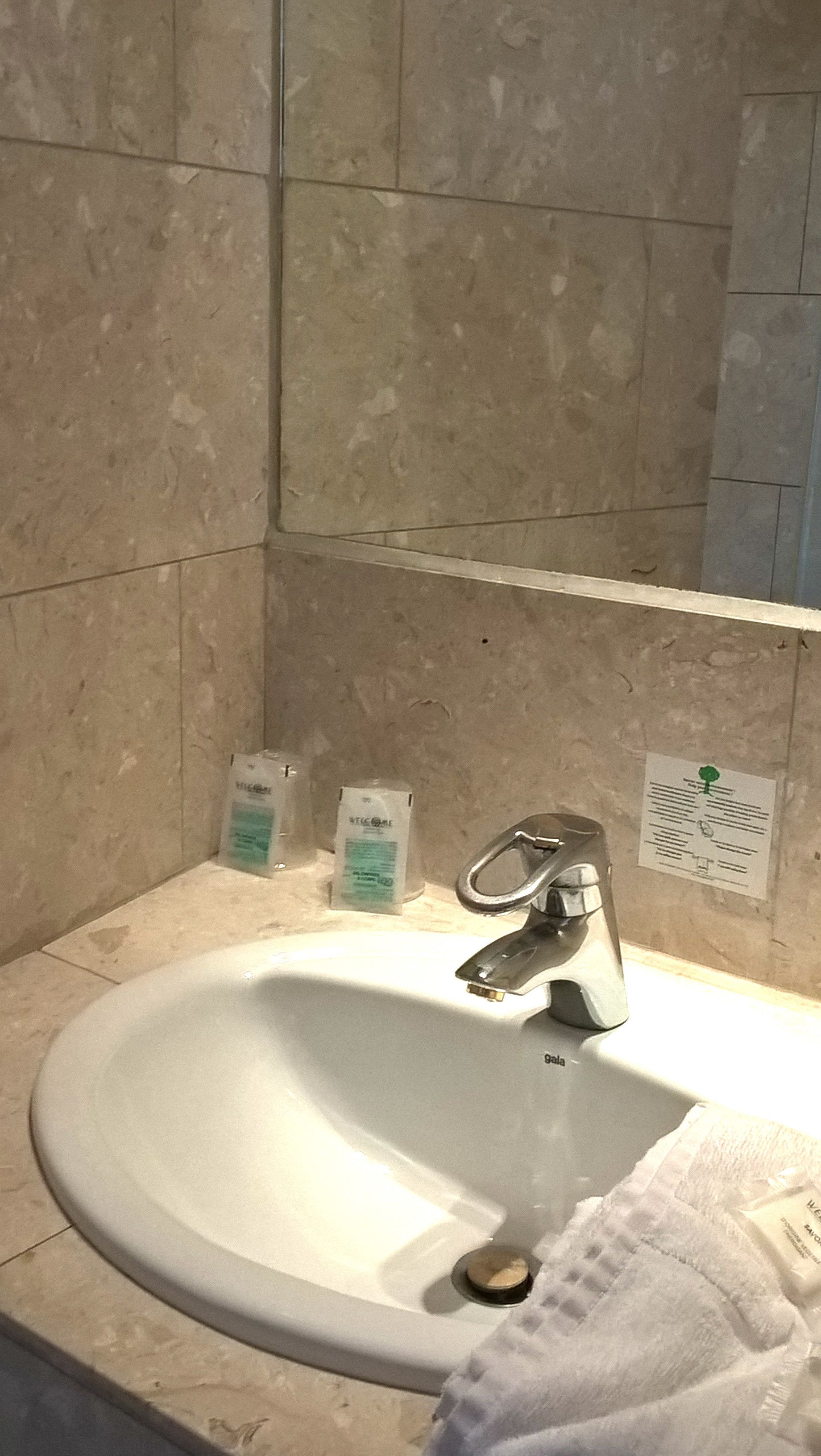 A bathroom sink with a mirror above it, a towel hanging on the wall, and toiletries on the counter.