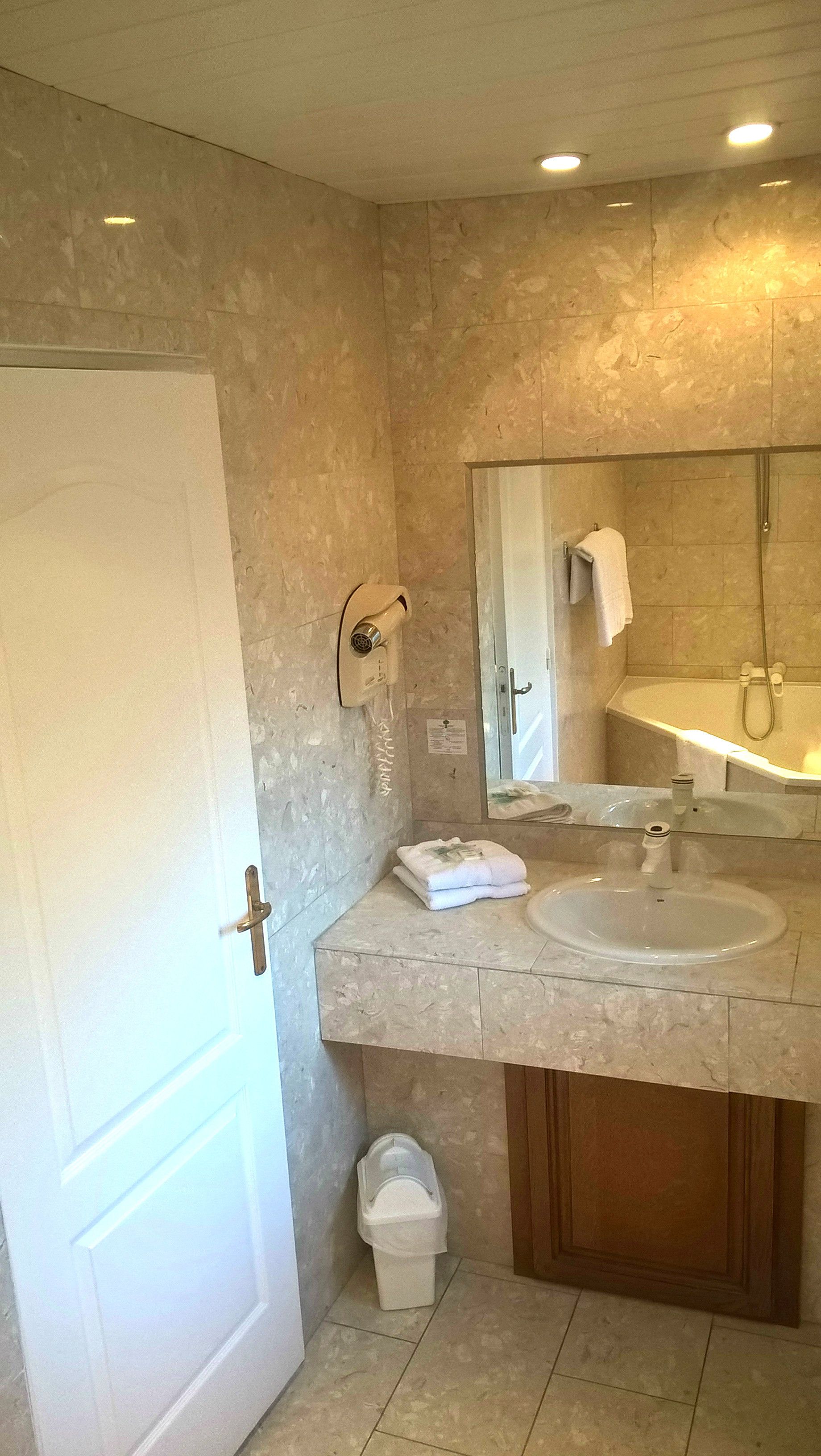 Un baño con puerta blanca, lavamanos, espejo, toallero y ducha.