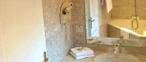 Un baño con puerta blanca, lavamanos, espejo, toallero y ducha.