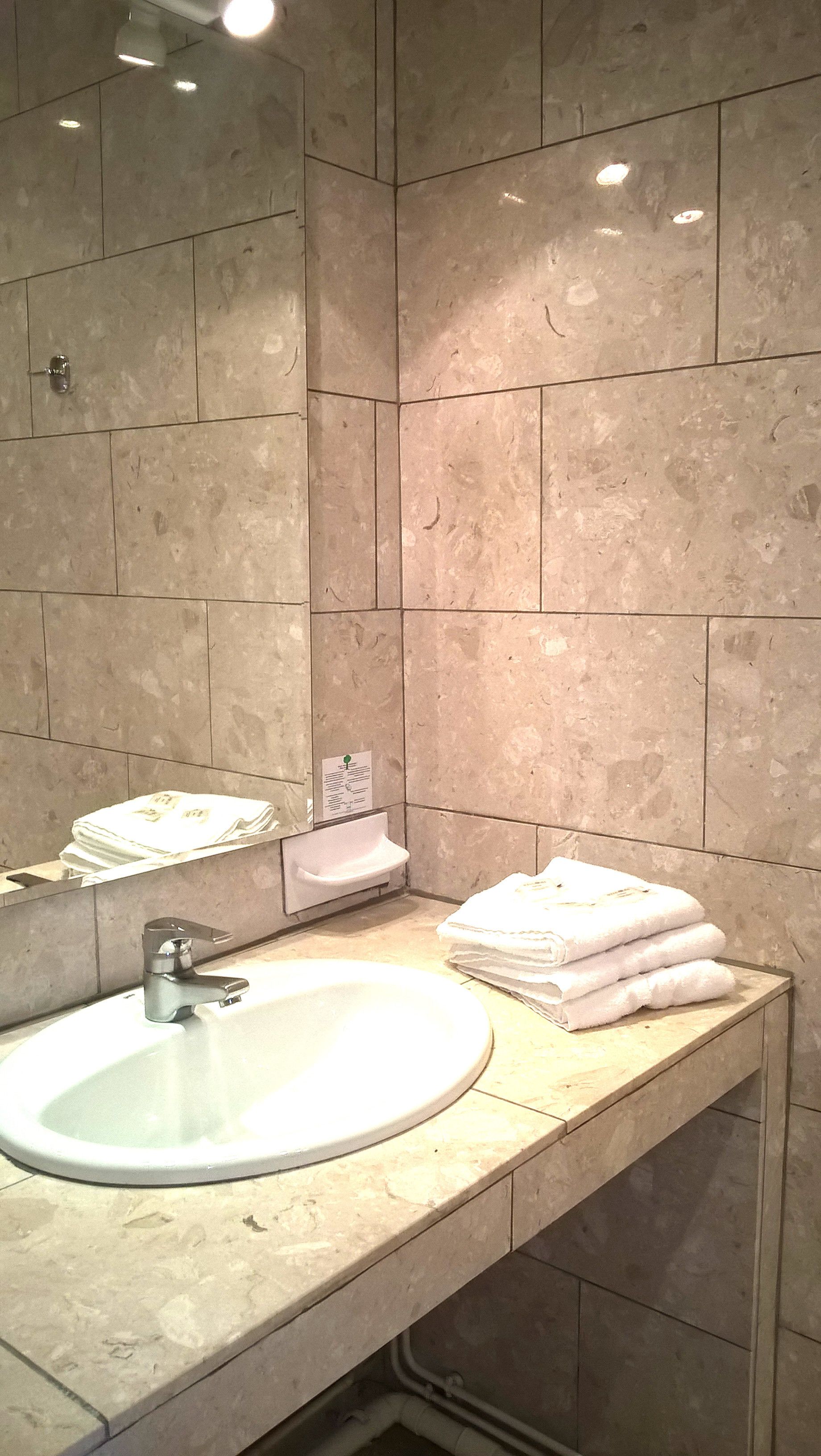 A bathroom with a sink, mirror, and towel stack.