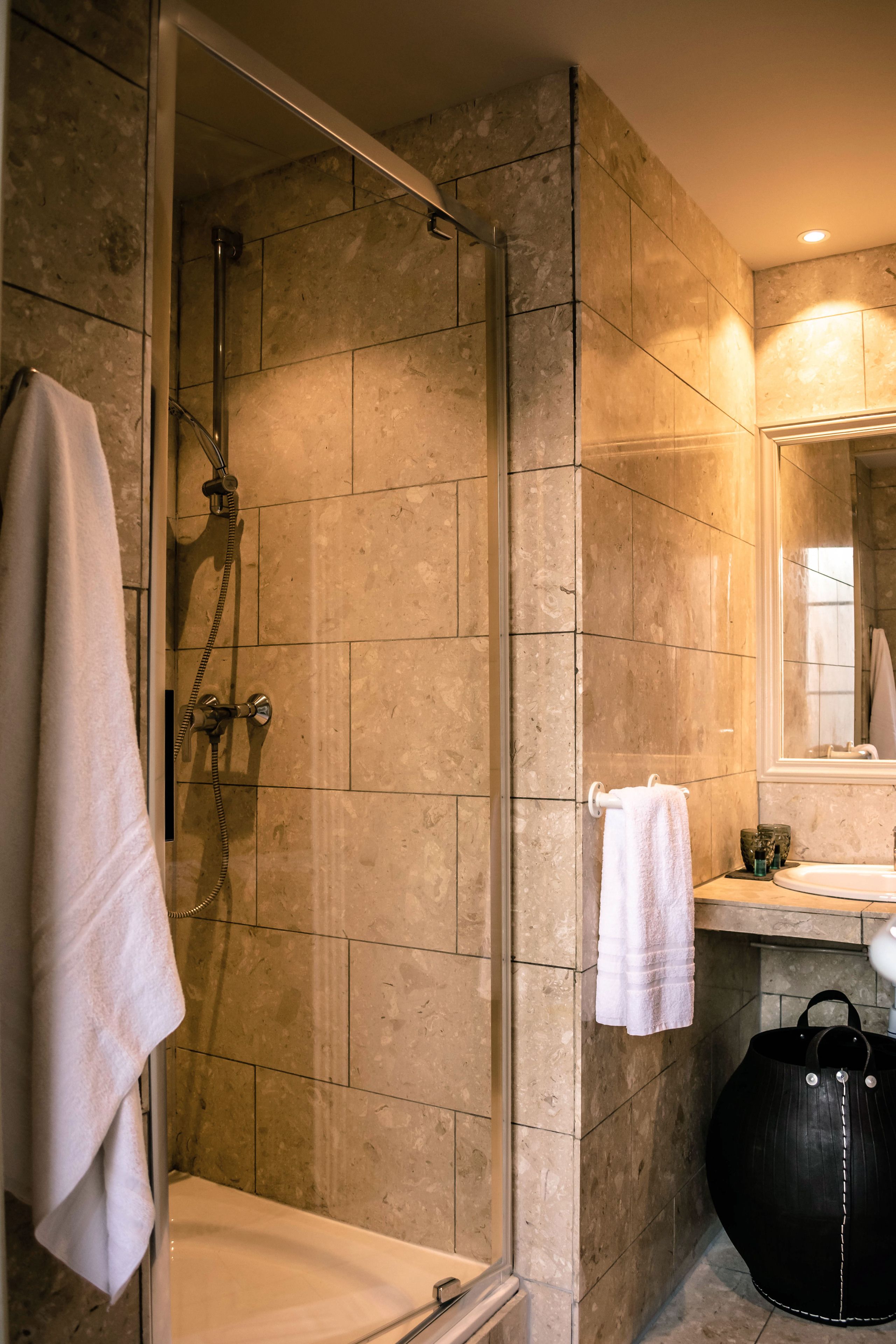 A bathroom with a glass-enclosed shower, a white sink, and a large black bag.