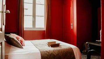 Een kamer met een bed, een raam en een deur.