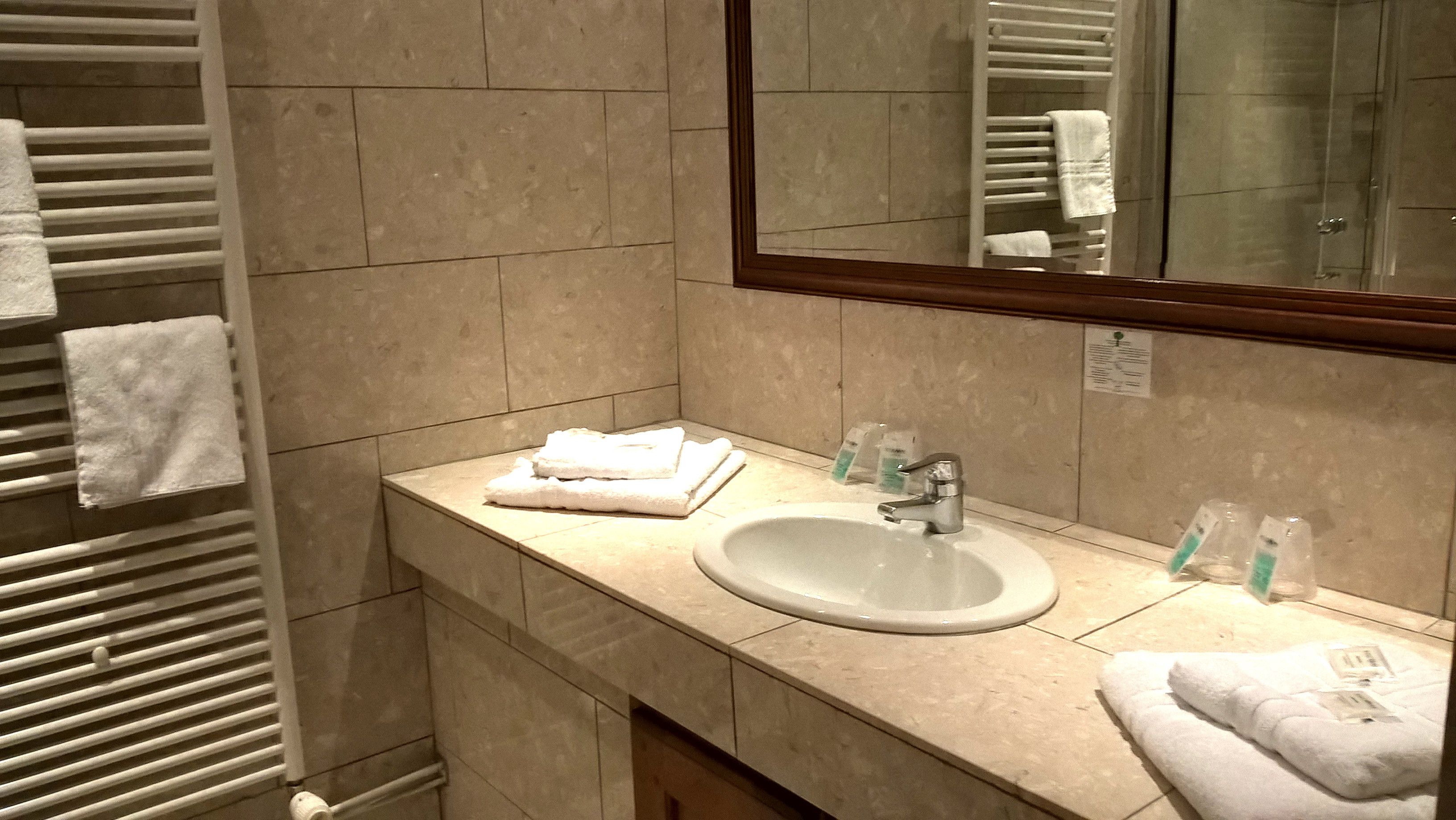 A bathroom with a sink, mirror, towel rack, and toiletries.