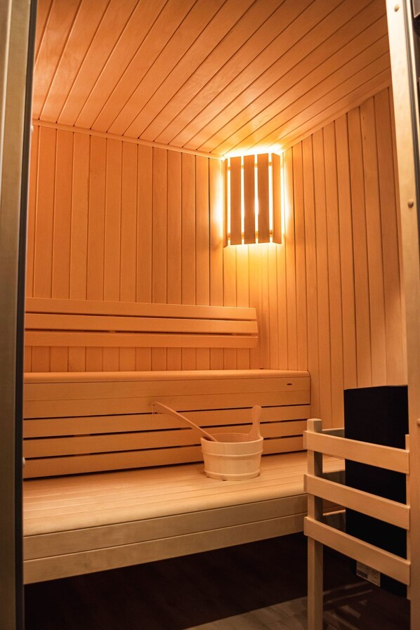 A sauna with wooden benches and a bench with a bucket and brush.