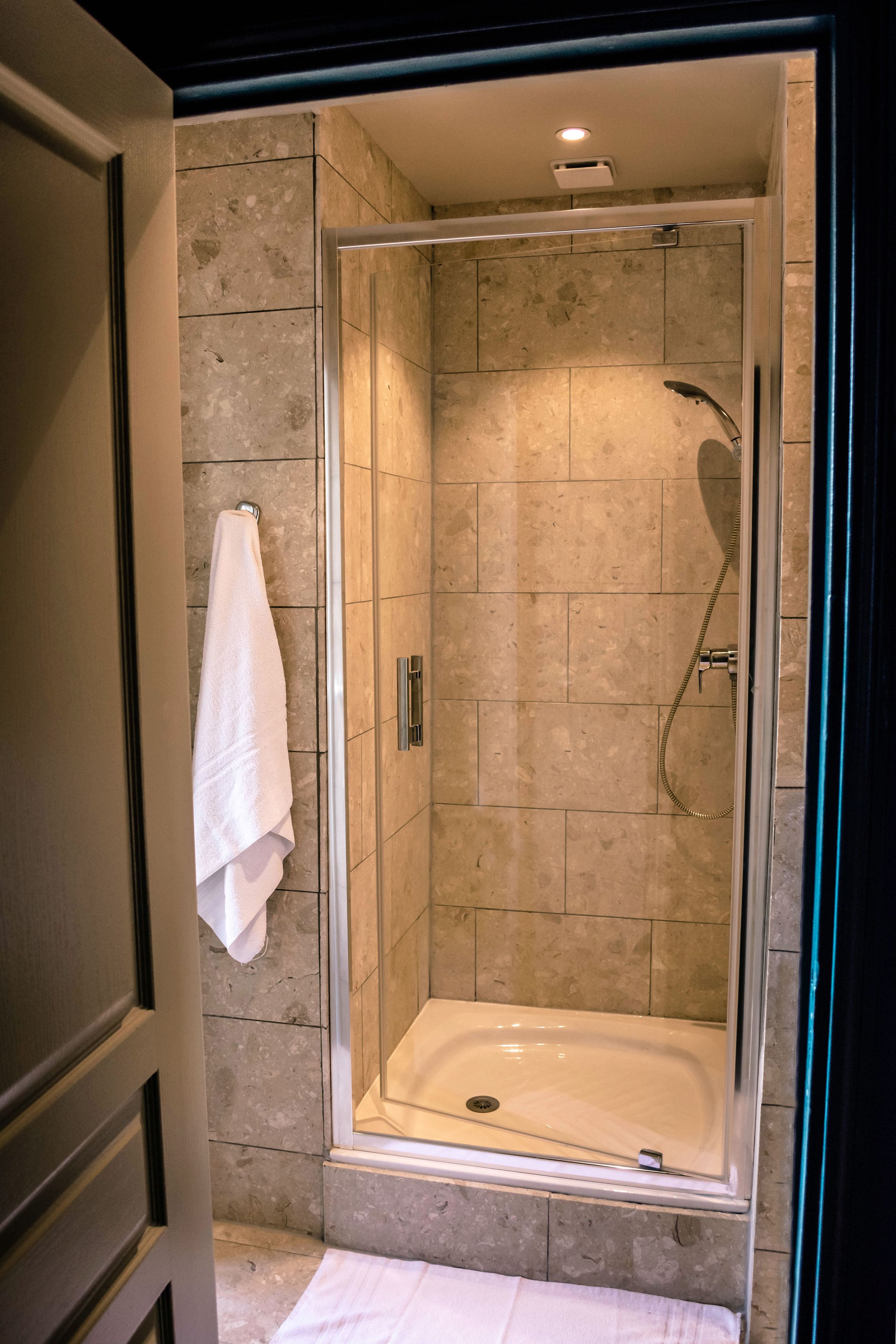 A glass-enclosed shower with a white sink and a towel hanging on the wall.