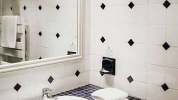 Un baño con un lavabo blanco, un espejo y una pared de azulejos con diseños de diamantes negros.