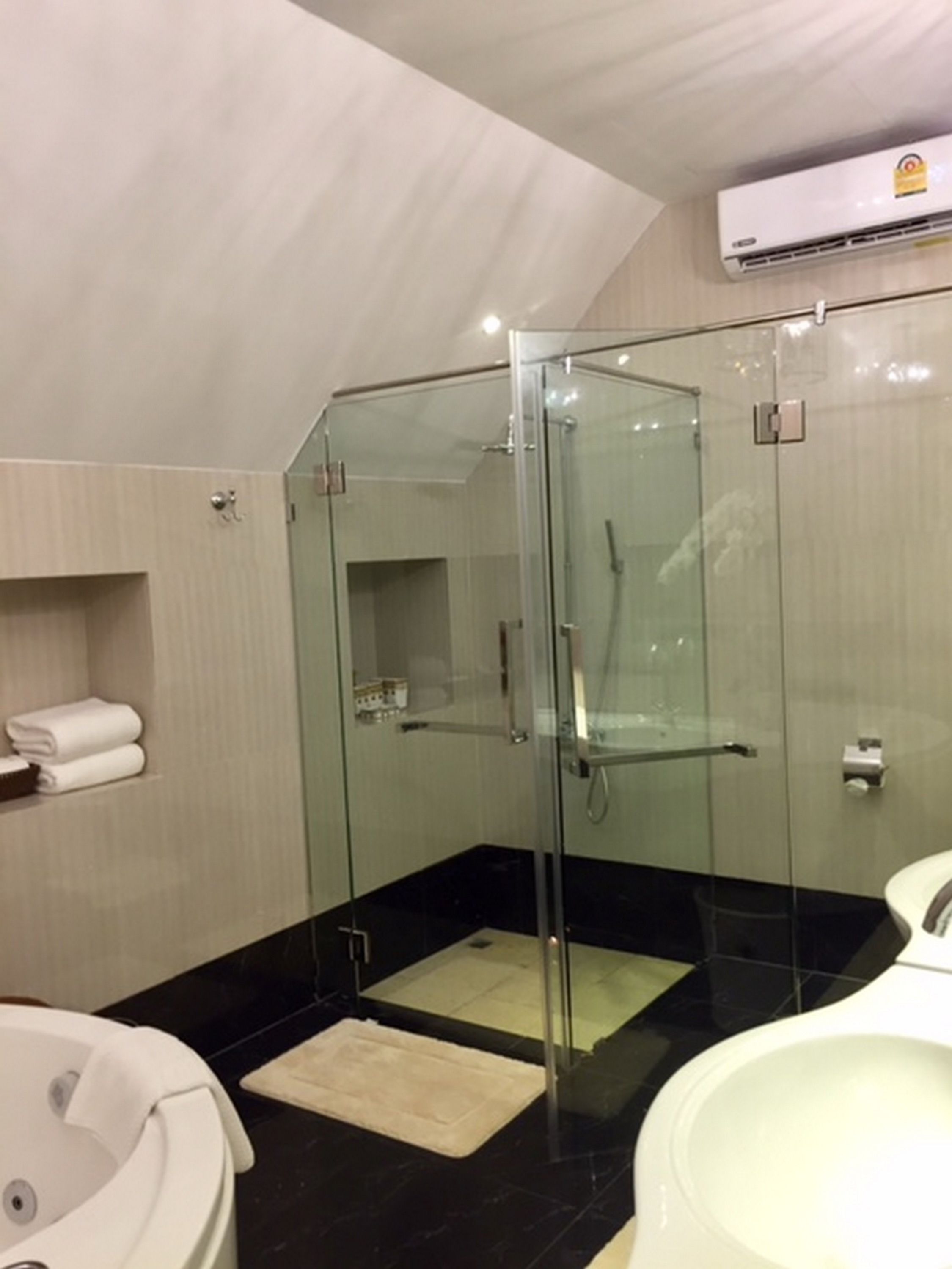 A modern bathroom with a glass-enclosed shower, a bathtub, and a toilet.