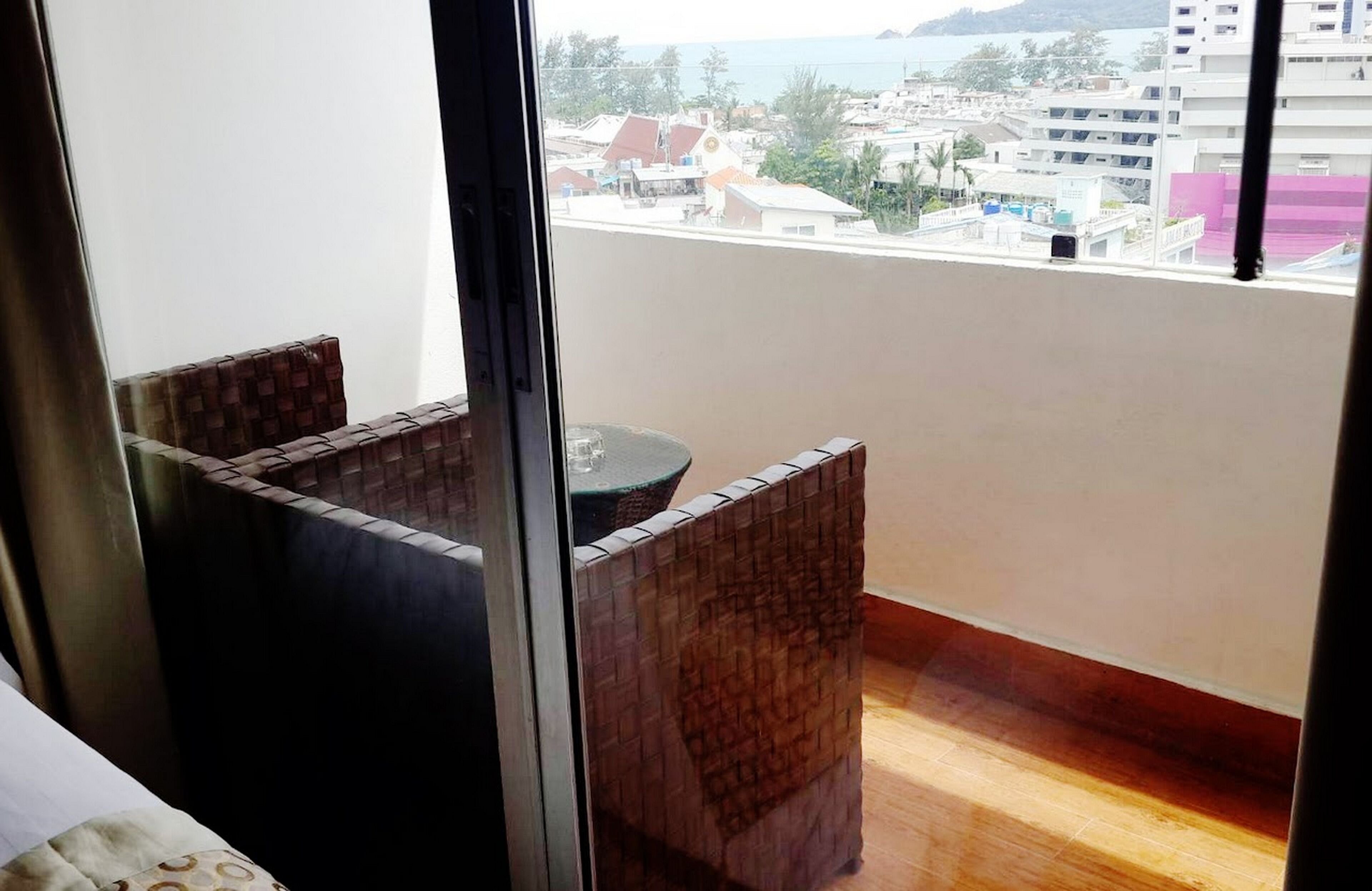 Un balcón con vistas a un pueblo costero, una mesita y una silla.