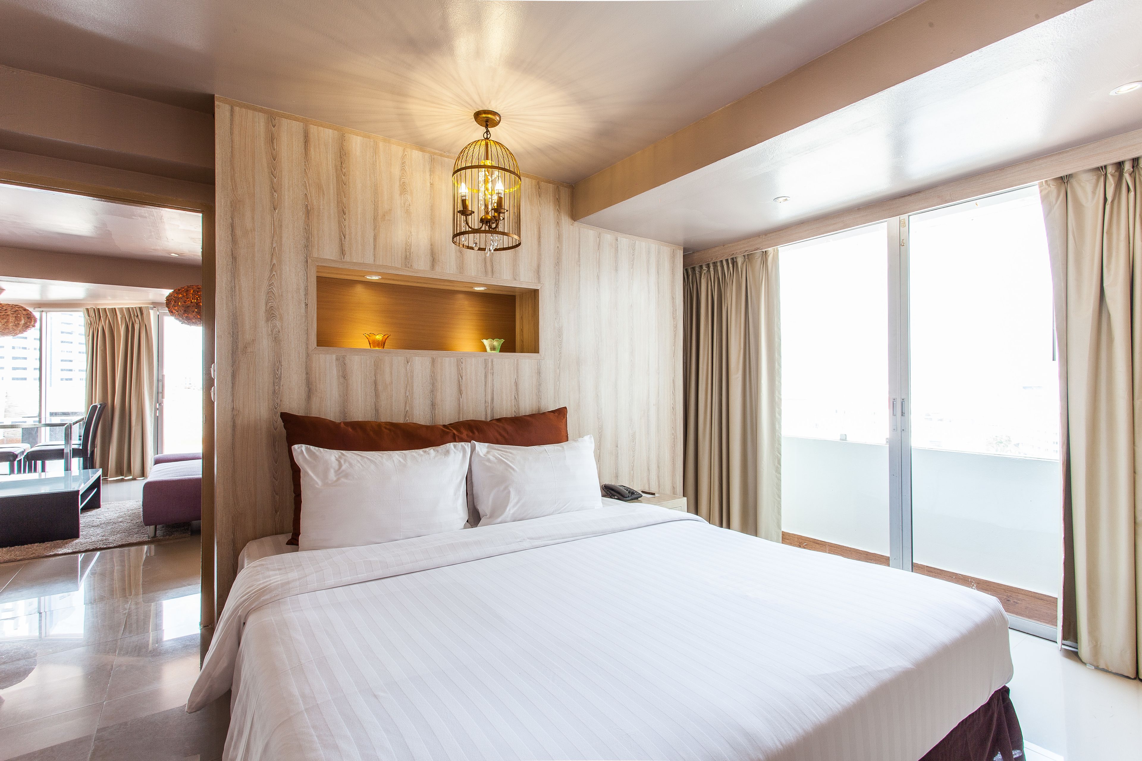 Una cama grande con ropa blanca, cabecera de madera y estante empotrado con adornos.