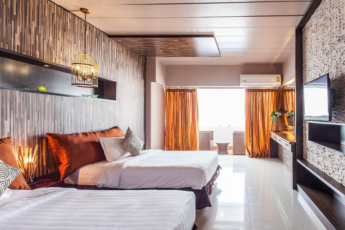 A modern hotel room with two beds, a TV, a fireplace, and a view of the outdoors.