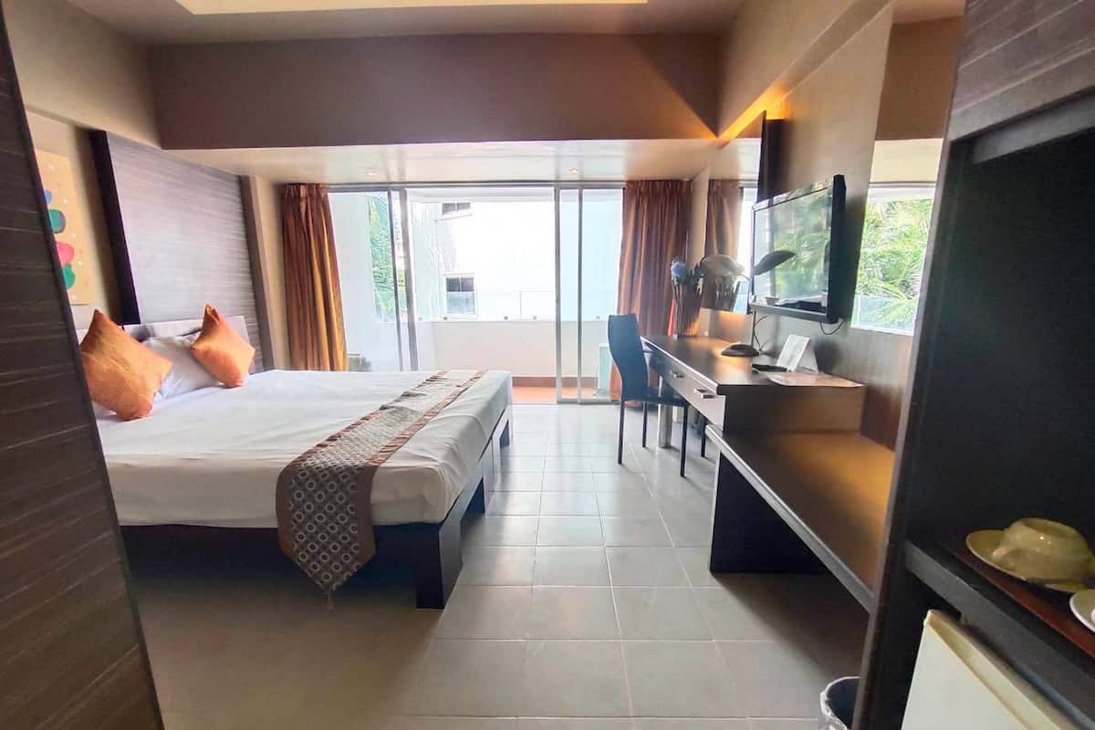 A hotel room with a bed, desk, chair, and a television.