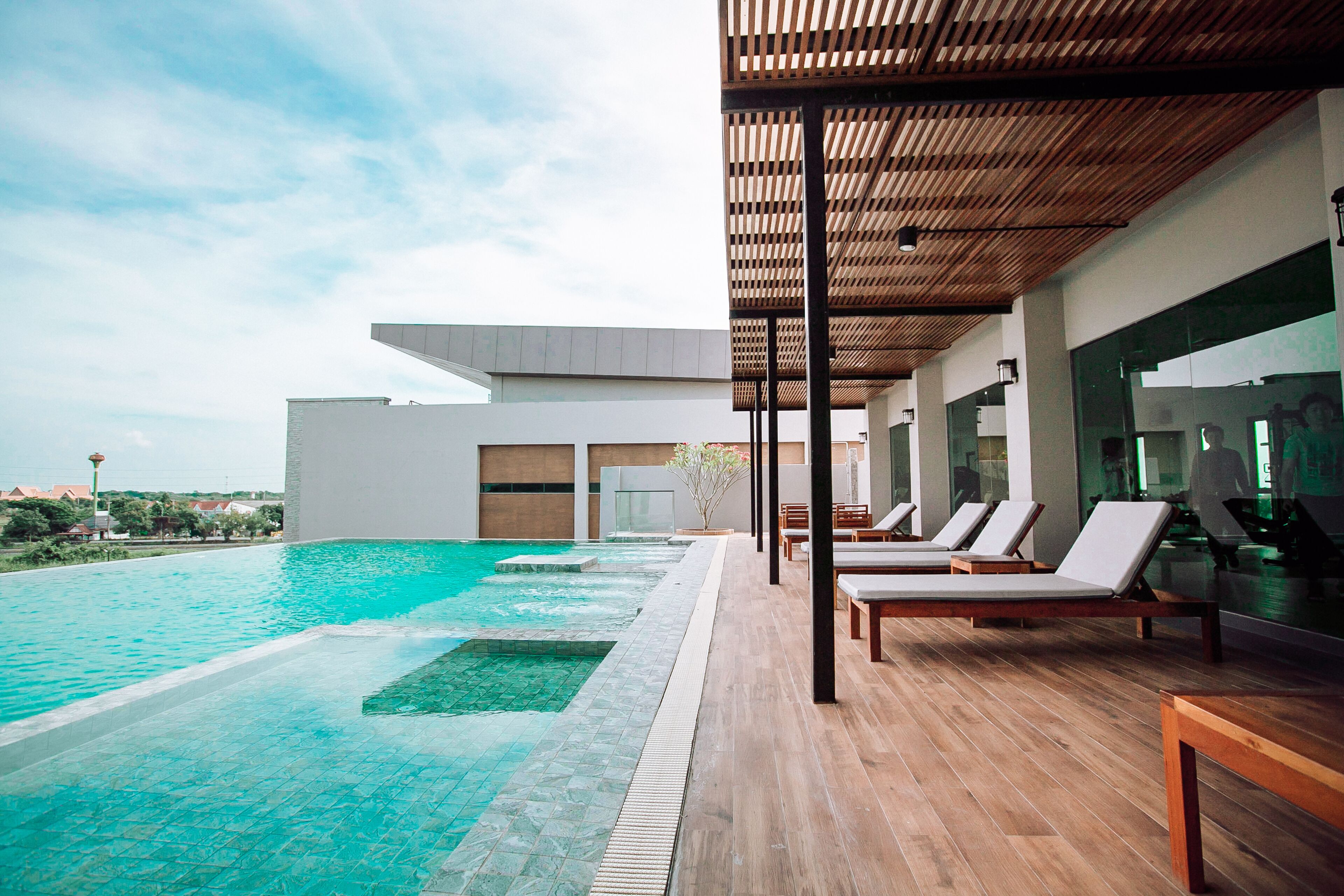 Un espace piscine moderne avec des chaises longues et une terrasse en bois.