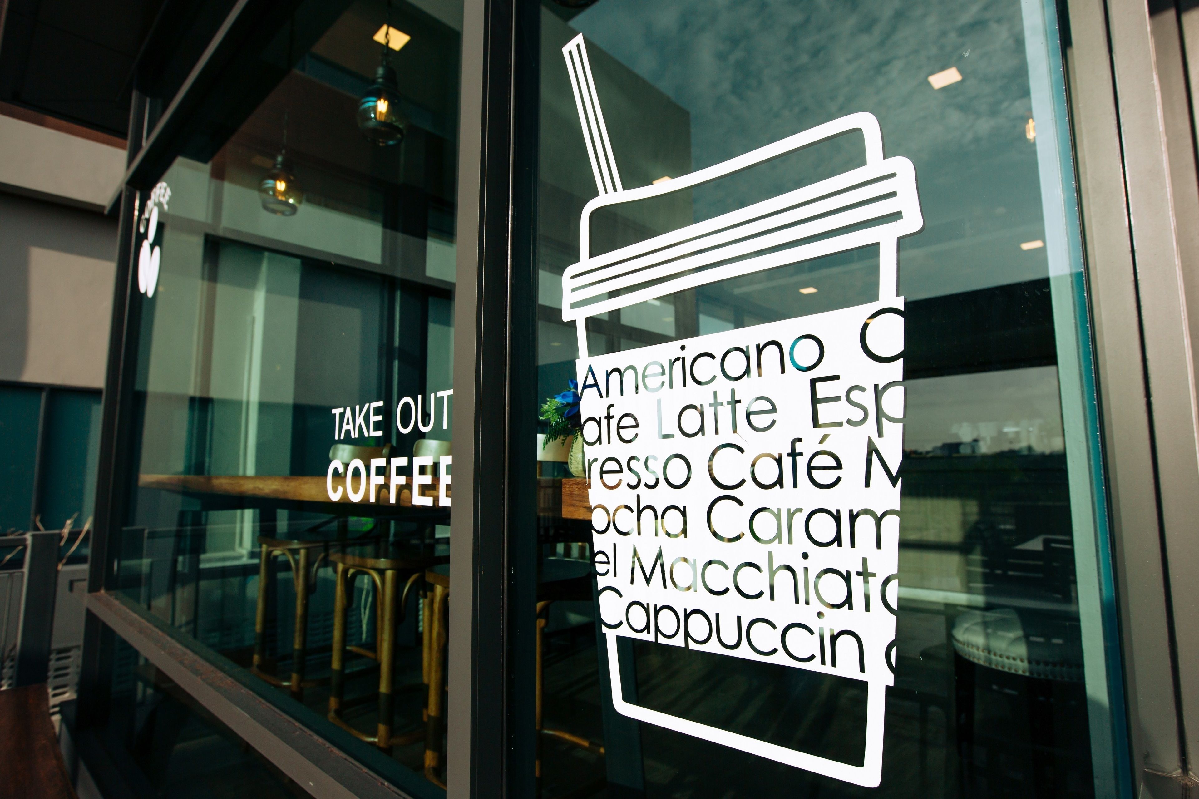 A window with a sign listing coffee types available at a cafe.