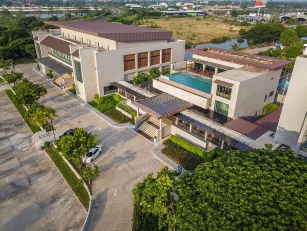 Un hotel moderno con piscina, un área exterior techada y estacionamiento.