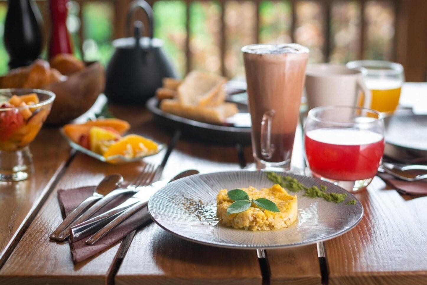 A dining table with a plate of food, a teapot, and various drinks.
