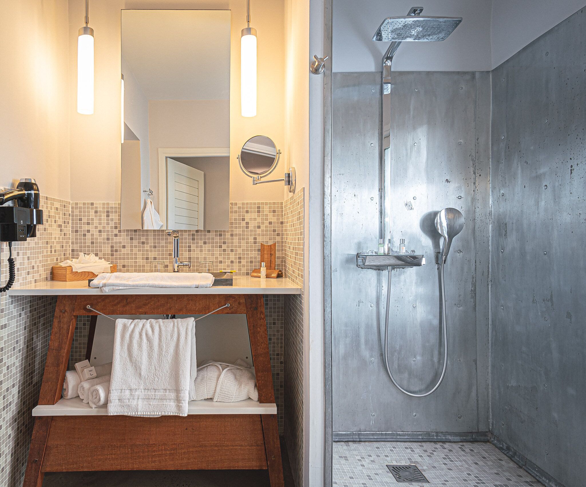 A bathroom with a sink, mirror, towel rack, and a shower with a handheld showerhead.