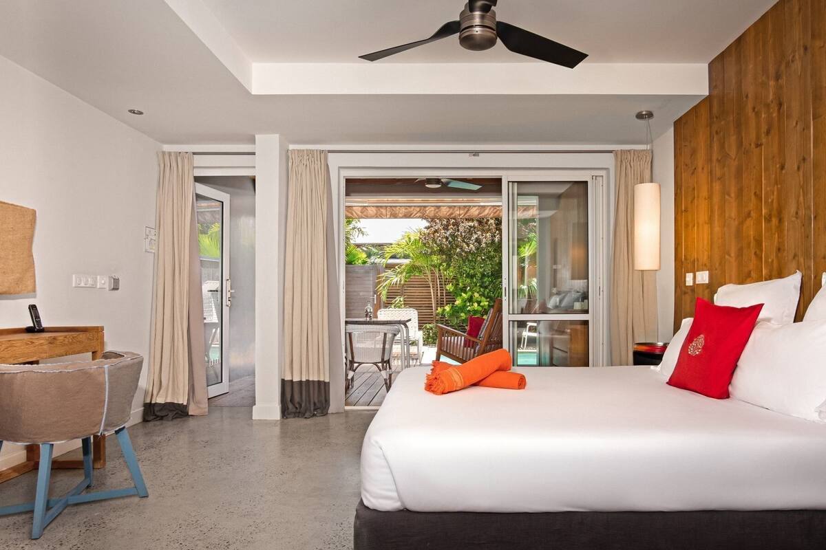 A hotel room with a bed, a desk, and a view of the outdoors.