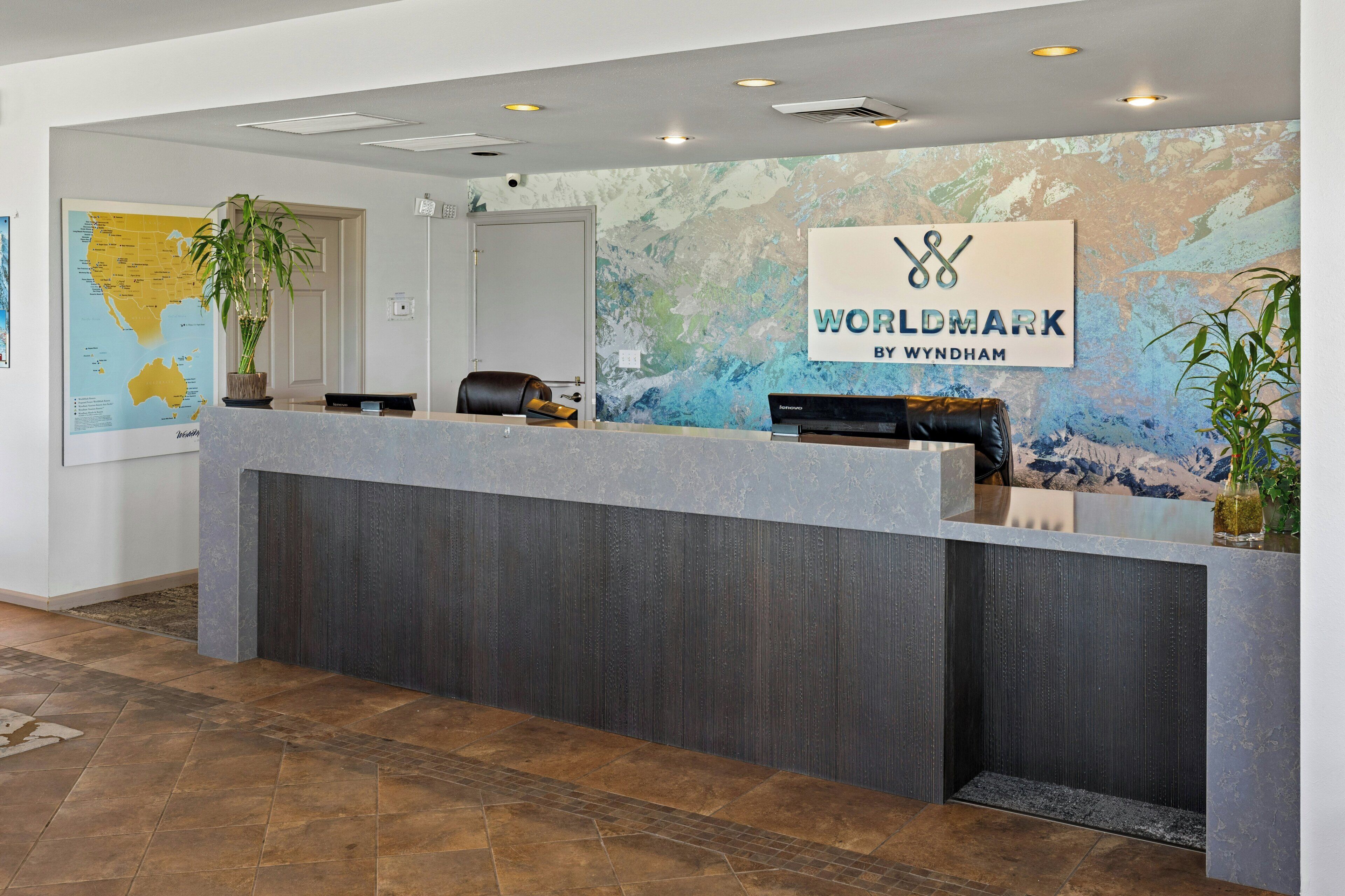 A reception desk with a 'WORLDMARK BY WYNDHAM' sign, a map, and a plant.